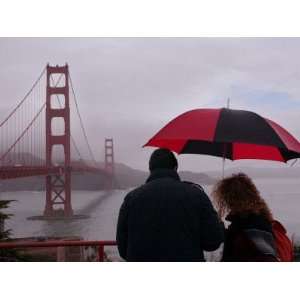  Tourists Use an Umbrella During a Light Rain, Looking at 